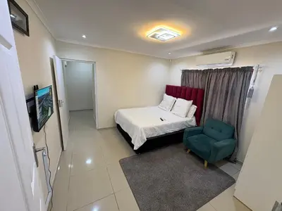 a small bedroom with a bed and a blue chair at Joy House in Cape Town