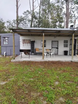 a small white house with a table and a patio at Stone Cottage in Grabouw