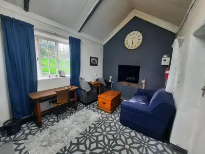 a living room with a blue couch and a clock on a wall at Stone Cottage in Grabouw