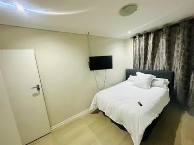 a bedroom with a bed and a tv on the wall at Joy House in Cape Town