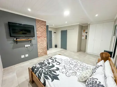 a bedroom with a bed and a tv on a wall at Blade Flatlet 2 in Silver Sands