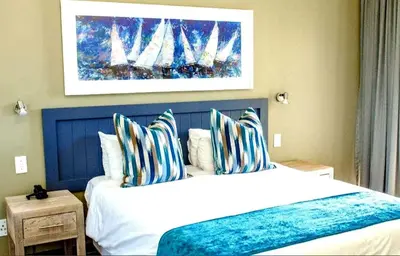 a bedroom with a large bed with striped pillows at The Strand Pavilion Gordon's Bay in Strand