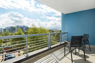 a balcony with two chairs and a view of a city at Modern 2 Bed Century City Apartment, Pool and Braai in Cape Town