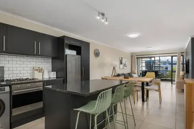 a kitchen with black cabinets and a table and chairs at Modern 2 Bed Century City Apartment, Pool and Braai in Cape Town