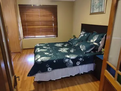 a bedroom with a bed with a green comforter and a window at Schubert Self Catering Accomodation in Brackenfell
