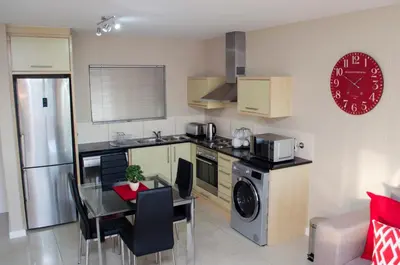 a kitchen with a table and a dining room at Knightsbridge Luxury Apartments in Cape Town