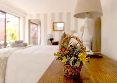 a basket of flowers sitting on a table next to a bed at Skye Cottage in Onrus River in Hermanus