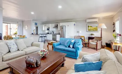 a living room with a couch and a table at Skye Cottage in Onrus River in Hermanus