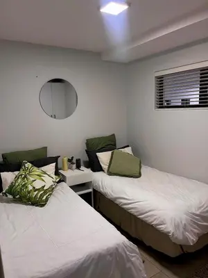 a bedroom with two beds and a mirror at Cosy Flat Steps from the Beach in Cape Town