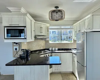 a kitchen with white cabinets and a black counter top at Ocean View in Hermanus