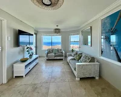a living room with a couch and a tv and windows at Ocean View in Hermanus