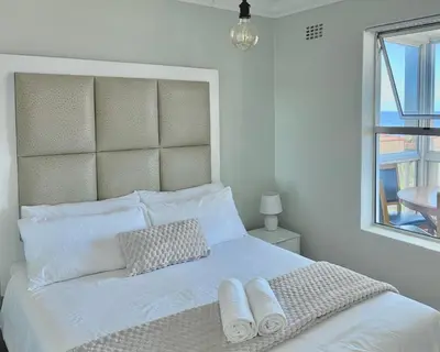a white bed with white pillows and a window at Ocean View in Hermanus