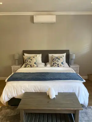 a bedroom with a large bed with a wooden table at Villa 121 Franschhoek Lermitage in Franschhoek
