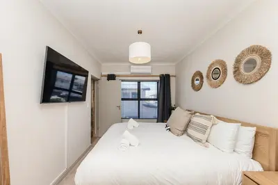 a bedroom with a white bed and a television at Cape On Viola 13-Blouberg Gem Walk to Kite Beach & Ocean Views in Cape Town