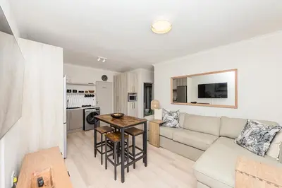 a living room with a couch and a table at Cape On Viola 13-Blouberg Gem Walk to Kite Beach & Ocean Views in Cape Town