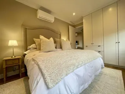 a bedroom with a large white bed and a night stand at Villa Mignon in Franschhoek