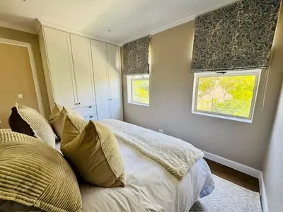 a bedroom with a bed and two windows at Villa Mignon in Franschhoek