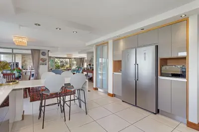 a kitchen with white cabinets and a table and chairs at Dune Pavillion Beach Villa-Where the Ocean Meets the Mountain in Cape Town