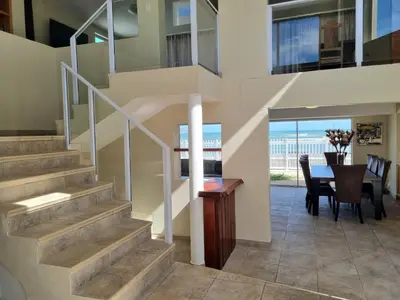 a staircase in a house with a dining room and a table at Paradise Tide - 4 Bedroom Beachfront home with Private Pool in Cape Town