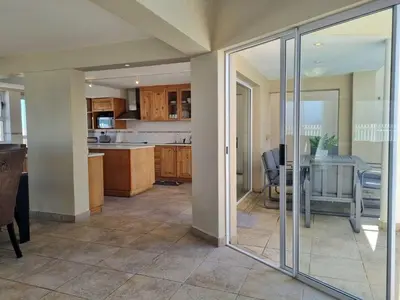 a kitchen with sliding glass doors and a table at Paradise Tide - 4 Bedroom Beachfront home with Private Pool in Cape Town