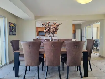 a dining room table with chairs and a vase of flowers at Paradise Tide - 4 Bedroom Beachfront home with Private Pool in Cape Town