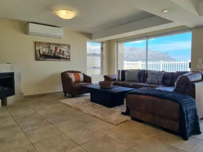 a living room with a couch and chairs and a fireplace at Paradise Tide - 4 Bedroom Beachfront home with Private Pool in Cape Town