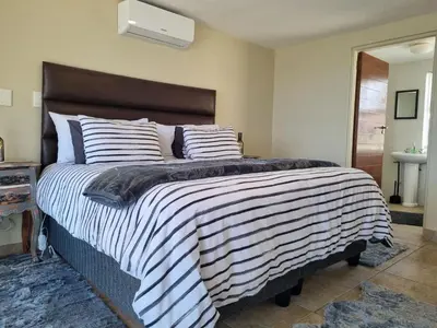 a bedroom with a large bed with striped blankets and pillows at Paradise Tide - 4 Bedroom Beachfront home with Private Pool in Cape Town