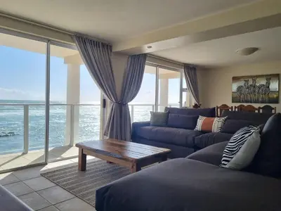 a living room with a blue couch and a table at Paradise Tide - 4 Bedroom Beachfront home with Private Pool in Cape Town