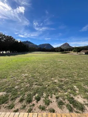 a large grass field with mountains in the background at Leliefontein Eco Cottage and Glamping in Paarl