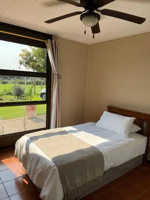 a bedroom with a bed with a ceiling fan and a window at Leliefontein Eco Cottage and Glamping in Paarl