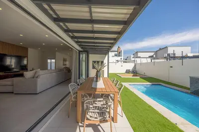 a living room with a table and a swimming pool at Cape Town Bliss in Sandown in Cape Town