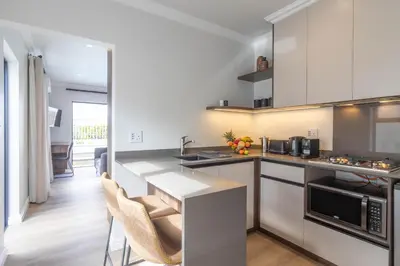 a kitchen with a counter and some chairs in it at Executive 1 bedroom Cottage, with aircon, king size bed and modern bathroom in Hermanus