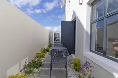 a small patio with chairs and a table on the side of a house at Executive 1 bedroom Cottage, with aircon, king size bed and modern bathroom in Hermanus