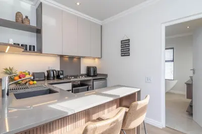 a kitchen with white cabinets and a counter top at Executive 1 bedroom Cottage, with aircon, king size bed and modern bathroom in Hermanus