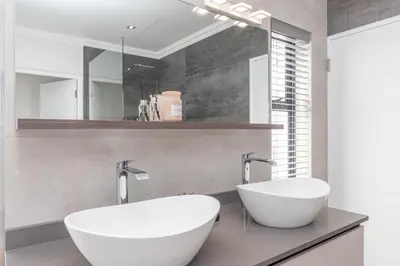 a bathroom with two sinks and a mirror at Executive 1 bedroom Cottage, with aircon, king size bed and modern bathroom in Hermanus