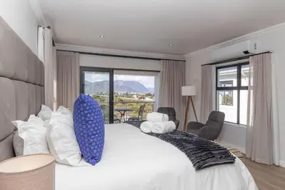 a bedroom with a large bed with a large window at Relax in comfort and style with a swimming pool, aircons and braai room in Hermanus