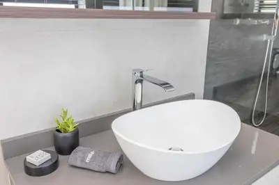 a bathroom with a white sink on a counter at Relax in comfort and style with a swimming pool, aircons and braai room in Hermanus