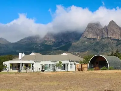 a large white building with mountains in the background at La Vita Romantic Getaway Cabin in Wellington