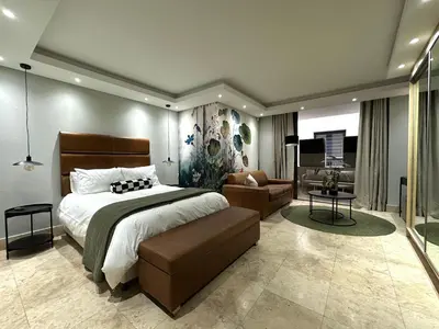a bedroom with a large bed and a living room at 109 on Oudehoek in Stellenbosch