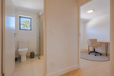 a bathroom with a toilet and a chair at Oakwood Hermanus in Hermanus