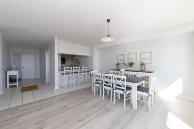 a kitchen and dining room with a table and chairs at Dolphin Beach C110 Beachfront Beauty in Cape Town