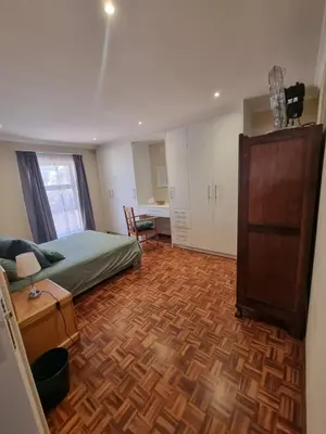 a bedroom with a bed and a wooden floor at Peaceful, Cheerful, Family Friendly 3Bedroom house in Edgemead