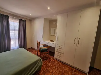 a bedroom with a bed and a desk and a chair at Peaceful, Cheerful, Family Friendly 3Bedroom house in Edgemead