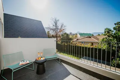a balcony with two benches and a table and a fence at Mountain-View Stay, Aircon, WiFi, Parking in Somerset West