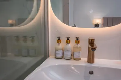 a bathroom sink with three bottles of soap at De Waal Grandeur Apartment in Stellenbosch