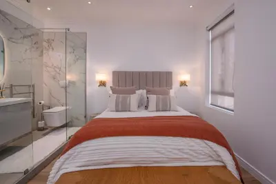 a bedroom with a large bed with a glass wall at De Waal Grandeur Apartment in Stellenbosch
