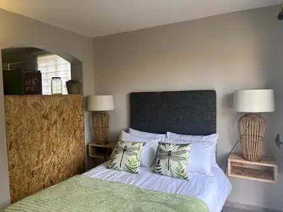 a bedroom with a bed with a green blanket and two lamps at The Dragonfly in Paarl