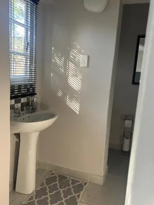 a white bathroom with a sink and a window at The Dragonfly in Paarl