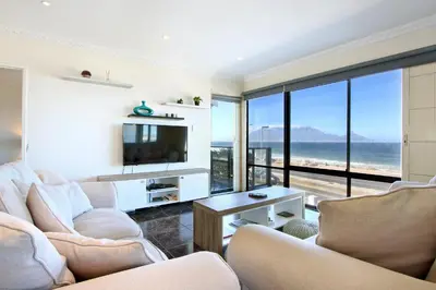 a living room with two chairs and a television at Cap Du Mont Cape Town in Bloubergstrand