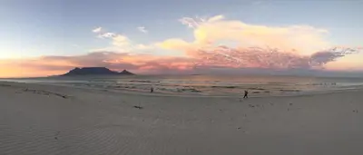 a person walking on the beach at sunset at Cap Du Mont Cape Town in Bloubergstrand
